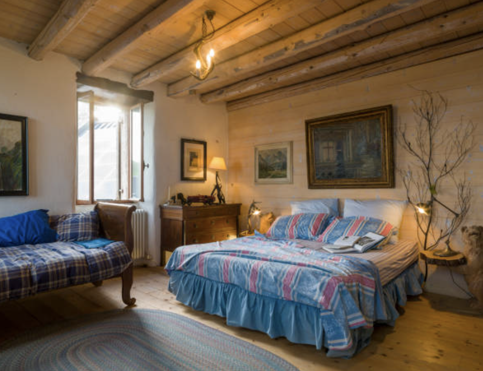 ログハウスのベッド＆ブレックファストのある部屋の様子。クイーンサイズベッドの足元にはラブチェアが置かれている。